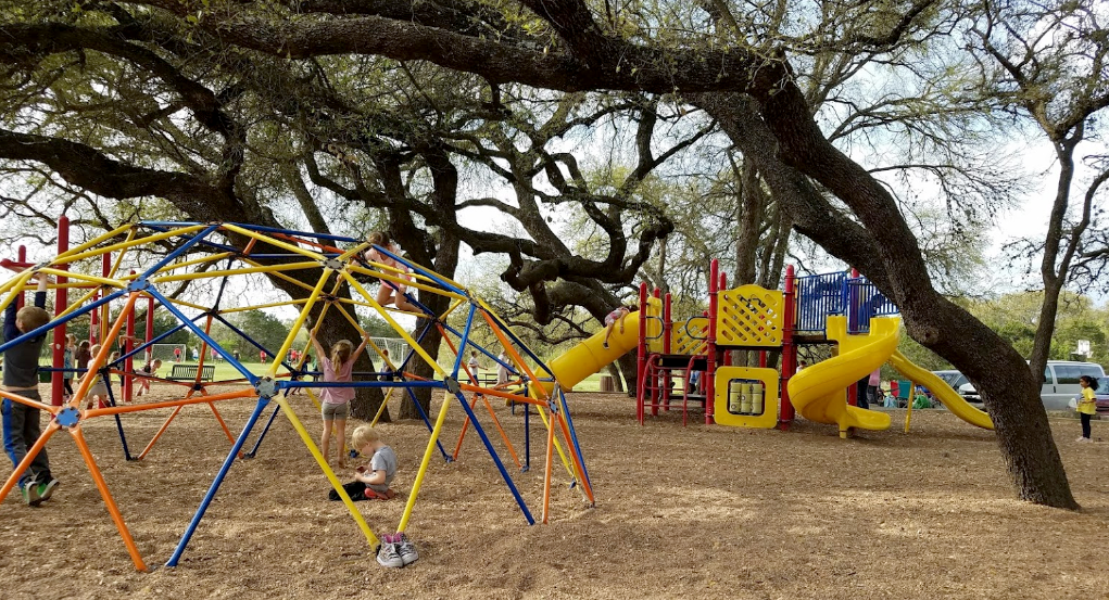 Large blue and yellow playscape. A jungle gym is in the foreground. 